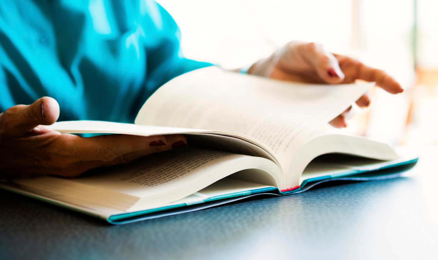 A senior woman's hand turning the pages of a book.